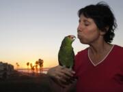 Mira Tweti, executive director of the national Parrot Care Project, kisses her rescue parrot, Liberty, at her Los Angeles apartment.