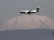 An Alaska Airlines plane flies past Mount St. Helens. Alaska Airlines wants federal approval to launch nonstop service from Portland to Reagan National Airport in Washington, D.C.