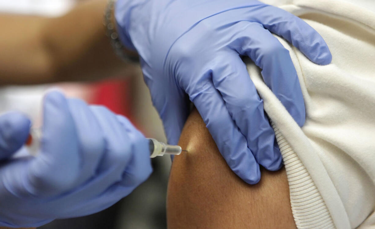 Victor Zamora, right, gets his Tdap shot from pediatric nurse practitioner Jenny Lu, right, in Tustin, Calif.