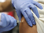 Victor Zamora, right, gets his Tdap shot from pediatric nurse practitioner Jenny Lu, right, in Tustin, Calif.