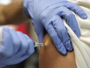 Victor Zamora, right, gets his Tdap shot from pediatric nurse practitioner Jenny Lu, right, in Tustin, Calif.