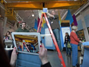 Washington State University Vancouver student Madi Kozacek, foreground left, points an iPad at an object representing the digital hot spots that will be installed on a display automobile at the Oregon Museum of Science and Industry in Portland. OMSI's Jeff Varner, center, holds the object at the appropriate height. At right is WSUV student Jason Clark.