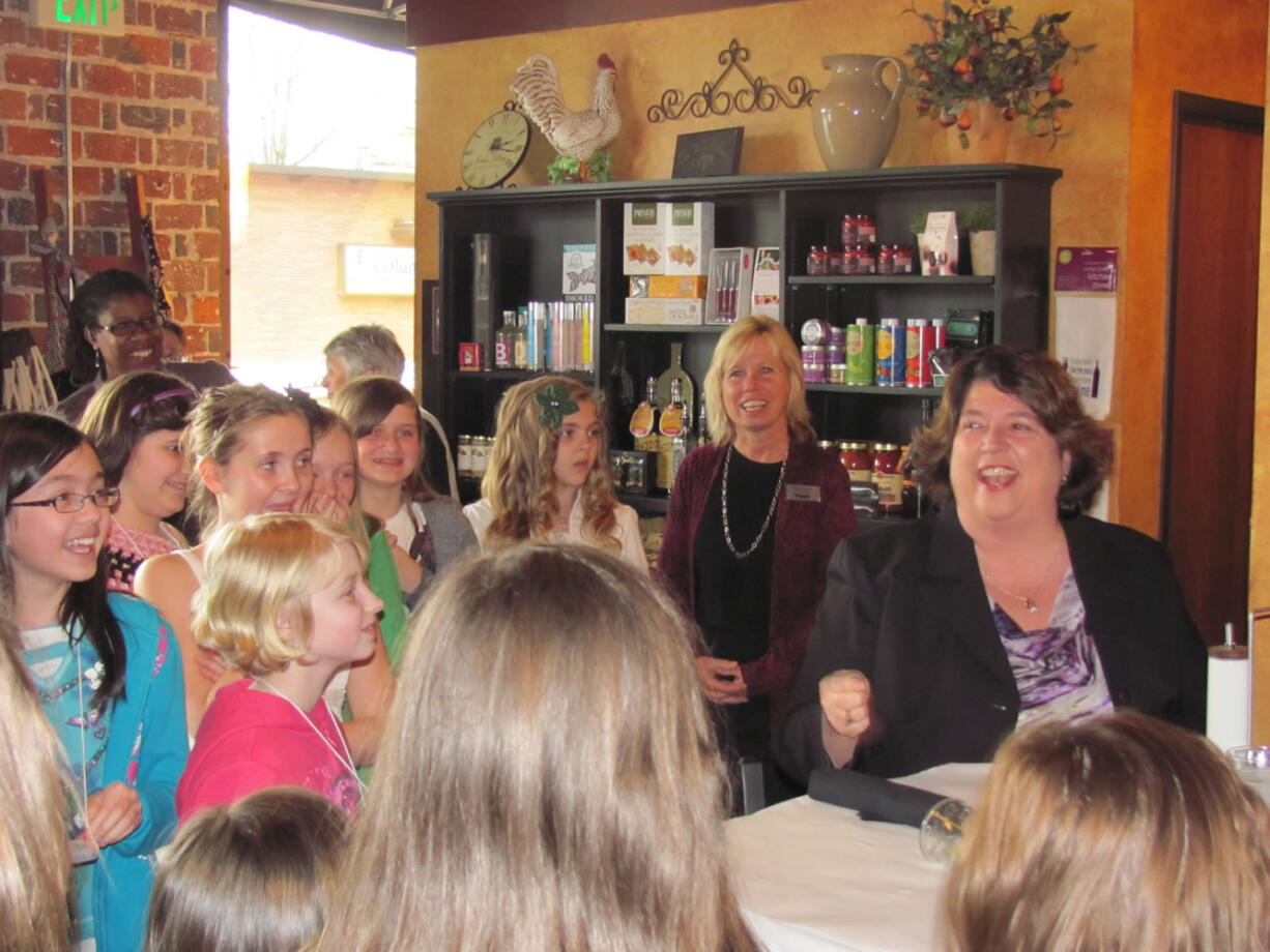 Linda Haines (seated) enjoys a laugh with several fifth-grade girls from Hathaway Elementary School during her &quot;bad manners&quot; skit at K'Syrah restaurant in Camas.