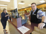 Liquor store employee Eric Simonson helps customer Andrea Gecho on Monday at the state-owned liquor store at 1700 Main St. in Vancouver.