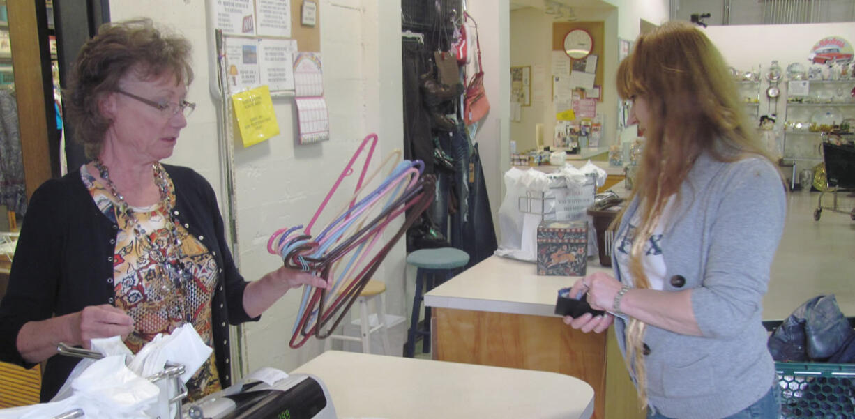 A volunteer assists a customer with a purchase at the Inter-Faith Treasure House thrift store, in Washougal.