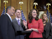 House Speaker John Boehner of Ohio,left, re-enacts the swearing in of Rep. Jaime Herrera Beutler, R-Camas, wearing red, in 2011 on Capitol Hill.