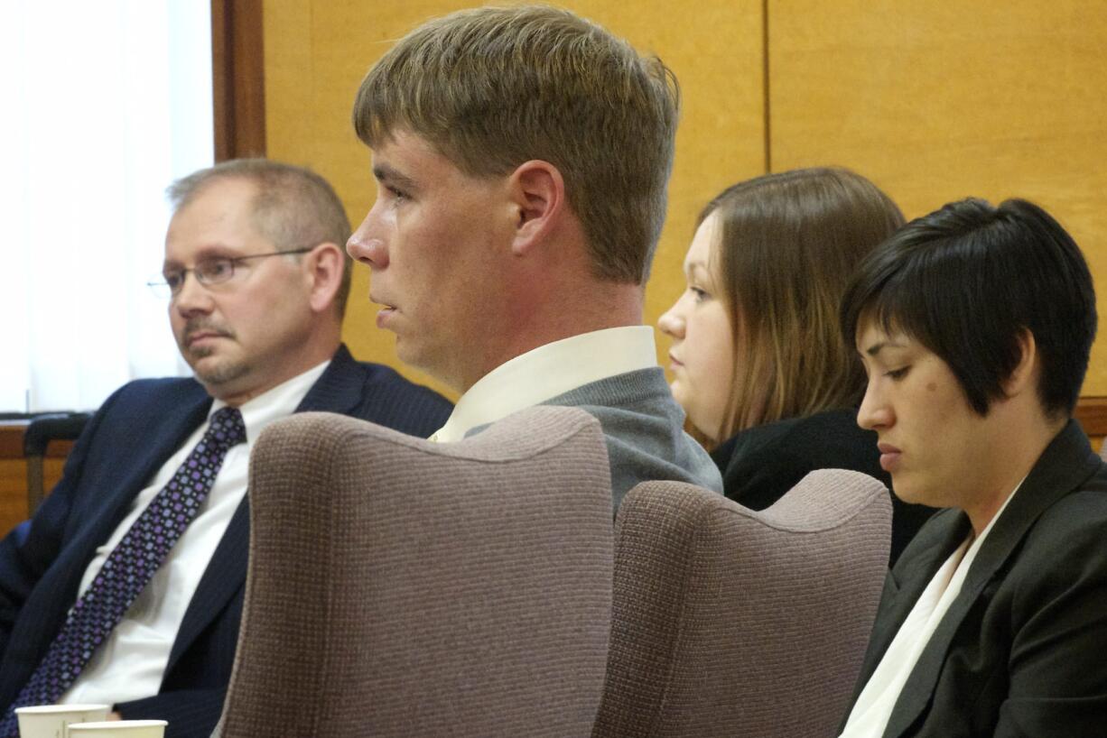 John Eckhart, center, and Alayna Higdon, center right, listen to opening statements Monday in Vancouver in a trial in which the couple are accused of locking up their two young autistic boys in a caged room.