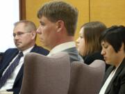 John Eckhart, center, and Alayna Higdon, center right, listen to opening statements Monday in Vancouver in a trial in which the couple are accused of locking up their two young autistic boys in a caged room.