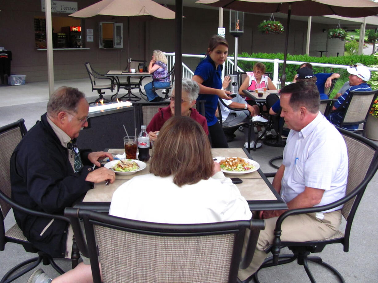 Guests enjoy salads and beverages by a warm fire Friday, during the grand opening of the Lower Terrace restaurant at Camas Meadows.