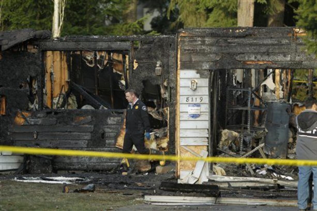 Pierce County Sheriff's deputies and Graham Firefighters work around the smoldering remains of a house near Fredrickson on Sunday, where, according to a sheriff's spokesman, three bodies were were found. The bodies are believed to be Josh Powell and his two sons.