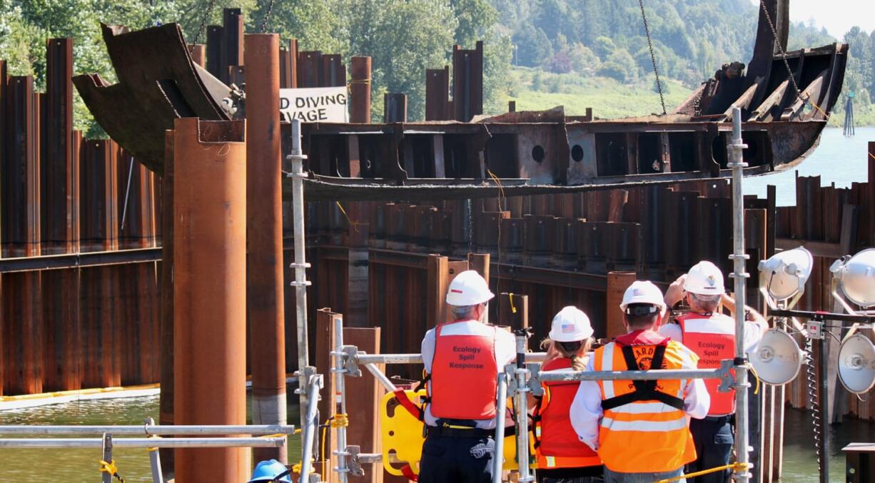 Spectators from &quot;Unified Command&quot; watch as the final 60-foot, 50,000 pound piece of steel from the derelict Davy Crockett vessel is lifted on Thursday from the Columbia River.