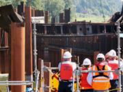 Spectators from &quot;Unified Command&quot; watch as the final 60-foot, 50,000 pound piece of steel from the derelict Davy Crockett vessel is lifted on Thursday from the Columbia River.