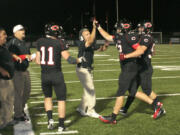 Camas High School football coaches and players congratulate John Norcross after his second touchdown Friday, at Doc Harris Stadium.