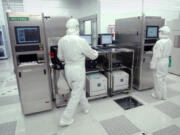 SEH America employees work on a silicon wafer manufacturing machine in the company's Vancouver plant.