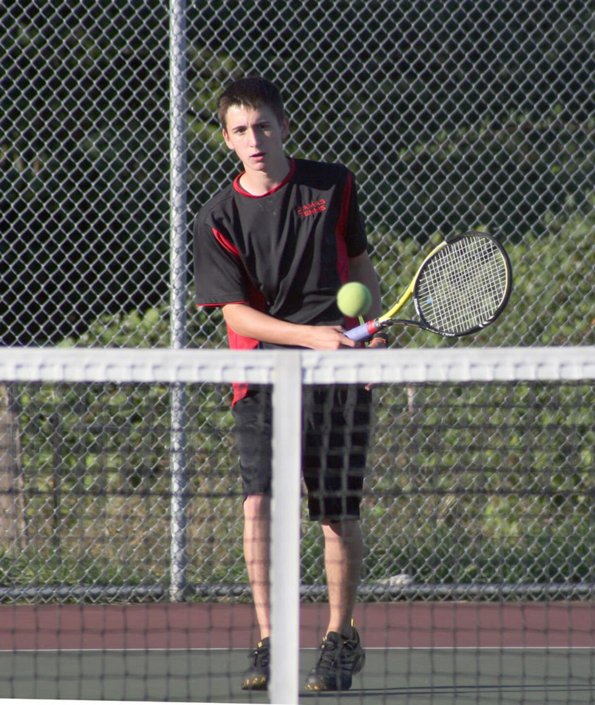 Gus Cooper lobs the tennis ball over the net for Camas Wednesday.