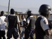 Police officers detain two demonstrators during a Christmas Eve protest at the Cite Soleil slum in Port-au-Prince, Haiti.