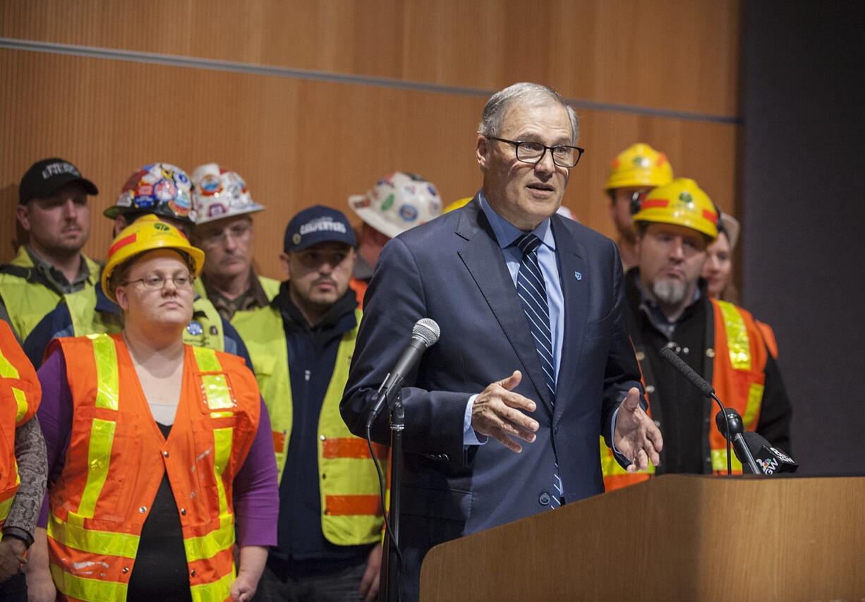 Democratic Gov. Jay Inslee, foreground, speaks to the crowd and the media Wednesday afternoon at the Vancouver Community Library.