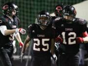 Camas players Zach Marshall (25) Jack Beall (left) and John Norcross (12) celebrate touchdown against Kennedy Catholic during 3A state tournament football game at Doc Harris Stadium.