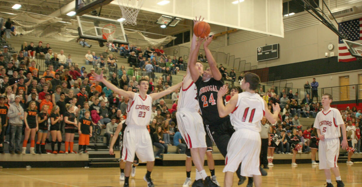 Washougal High School senior Mustapha Bah muscles up for a shot, while two Camas High School defenders try to stop him. The Panters defeated the Papermakers 64-44 Dec.