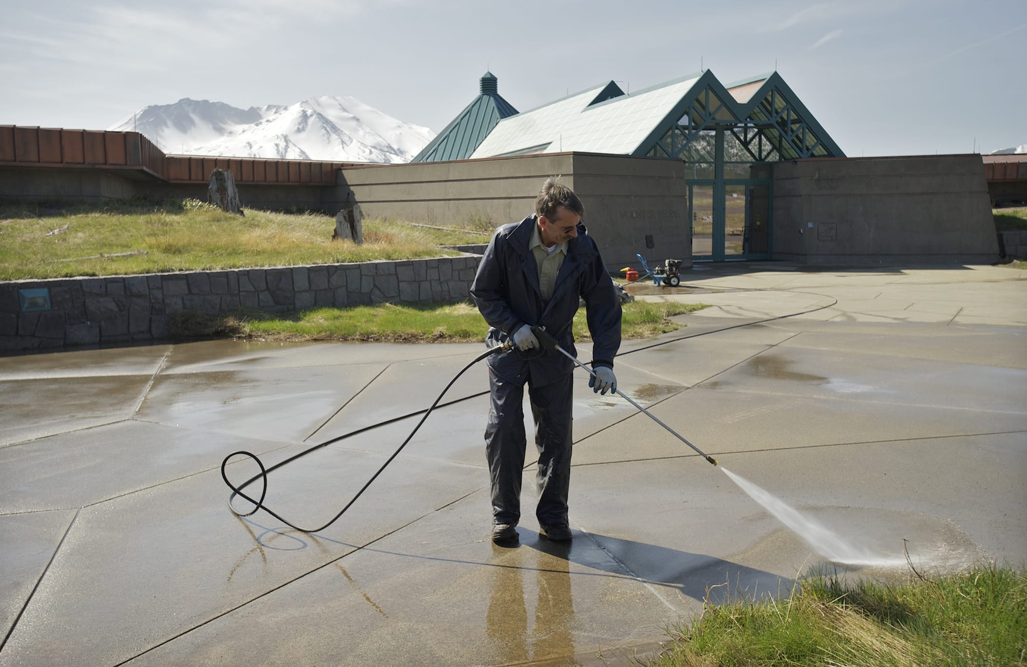 Roger Sadler of the U.S. Forest Service washes a walkway Friday outside the Mount St. Helens Science and Learning Center at Coldwater.