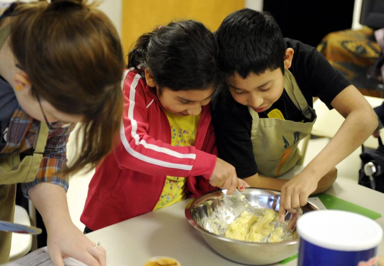 Seudy Bolon and her brother Alexander Bolon Manrero, right, mix dough for oatmeal cookies during a nutrition education class offered by a Vancouver food pantry.