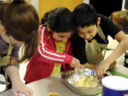 Seudy Bolon and her brother Alexander Bolon Manrero, right, mix dough for oatmeal cookies during a nutrition education class offered by a Vancouver food pantry.