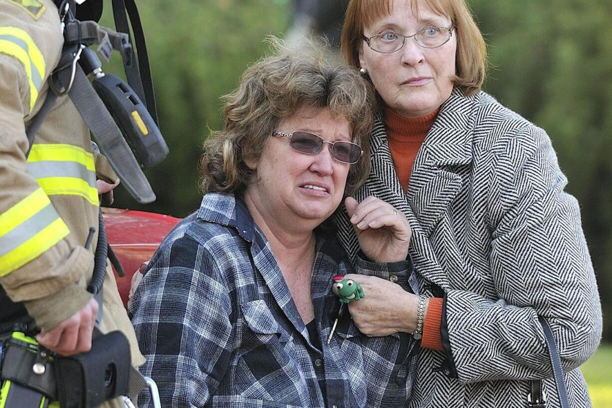 Neighbor Chris Newbrook, right, and acting captain Tom Schmaltz with Fire District 6, left, comfort Sandra Scovil, center, as she watches firefighters battle a blaze at her home Friday December 9, 2011 in Vancouver, Washington.