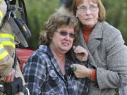 Neighbor Chris Newbrook, right, and acting captain Tom Schmaltz with Fire District 6, left, comfort Sandra Scovil, center, as she watches firefighters battle a blaze at her home Friday December 9, 2011 in Vancouver, Washington.