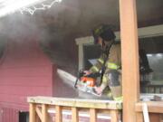 Firefighter Brian George cuts into the outside of a home where a wood stove insert and wood framing around it caught fire on Wednesday afternoon.