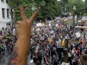 Pam Hogeweide, of Portland, throws up a peace sign, foreground, as protesters march north on SW Second Avenue from SW Jefferson Street in downtown Portland in solidarity with the national protests against wall street bailouts and corporate greed on Thursday October 6, 2011.