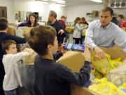 Alan Hamilton, the new executive director of the Clark County Food Bank, works with volunteers from Congregation Kol Ami, including Eli Mitchell-Hopmeier, center, and Zeke Mitchell-Hopmeier, left, as they unpack donations collected during the letter carriers food drive.