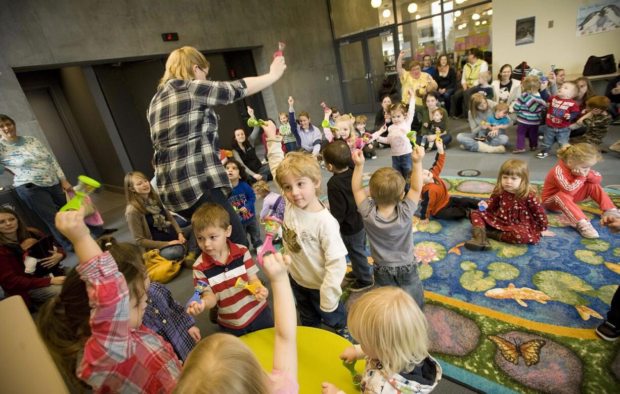 Kids shake rattles as children's librarian Kendra Jones leads them in song during Tuesday's toddler story time at the Vancouver Community Library.