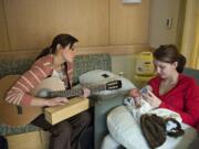 Music therapist Susan Palmieri, left, taps on a Gato box instrument as Haley Giese feeds her newborn son, Miles, a bottle Tuesday afternoon in PeaceHealth Southwest Medical Center&#039;s neonatal intensive care unit. Palmieri uses the Gato box to help Miles pace his sucking while feeding.