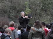 Michael Foster, a volunteer who started Plant for the Planet in Seattle, explains how to plant a Douglas fir seedling at Columbia Springs on Saturday. Sponsored by the United Nations, the event trains children and teens to become Ambassadors for Climate Justice.