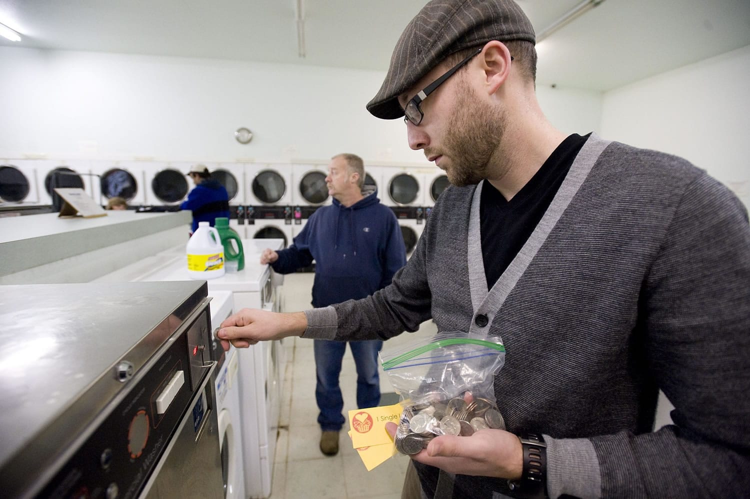 Jason Twyman, an elder at Camas Friends Church, feeds quarters into a machine at Riverside Laundry.