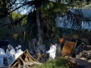 Investigators work the scene where a day earlier a man with a gun held police and firefighters off while a house burned to the ground in Washougal on Thursday December 8, 2011.