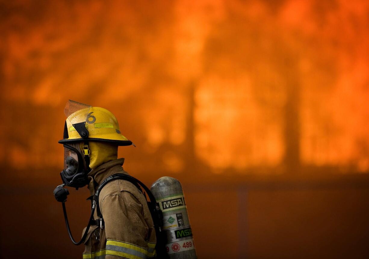 A firefighter walks by the fire-engulfed Central School in Battle Ground during a training exercise Saturday.