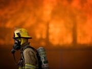 A firefighter walks by the fire-engulfed Central School in Battle Ground during a training exercise Saturday.