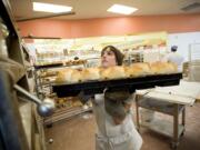 Lauren LaMotte, 30, from Portland, pulls bread from the oven Tuesday at the North Interstate New Seasons in Portland.