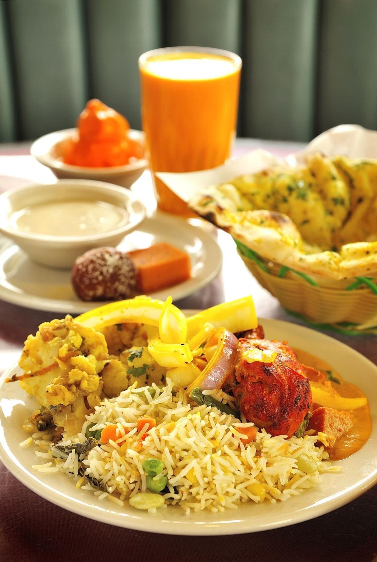 Clockwise from back left: Mango Ice Cream, Mango Lassi, Garlic Nan bread, Tandoori Chicken, Vegetable Biryani, Masala Aloo Gobi, Kheer rice pudding and Gulab Jamuns are among the abundant and colorful offerings at Namaste Indian Cuisine in Vancouver.