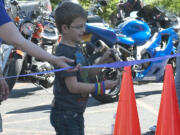 Fisher's Landing: Austin Vellek, son of Sharla and Rolf Vellek, cut the ribbon at the start of the Children's Cancer Association JoyRide.