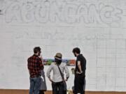 Volunteers Colin Cushman, from left, Jenney Pauer and Greg Bee help plan and paint a mural on the side of the St.