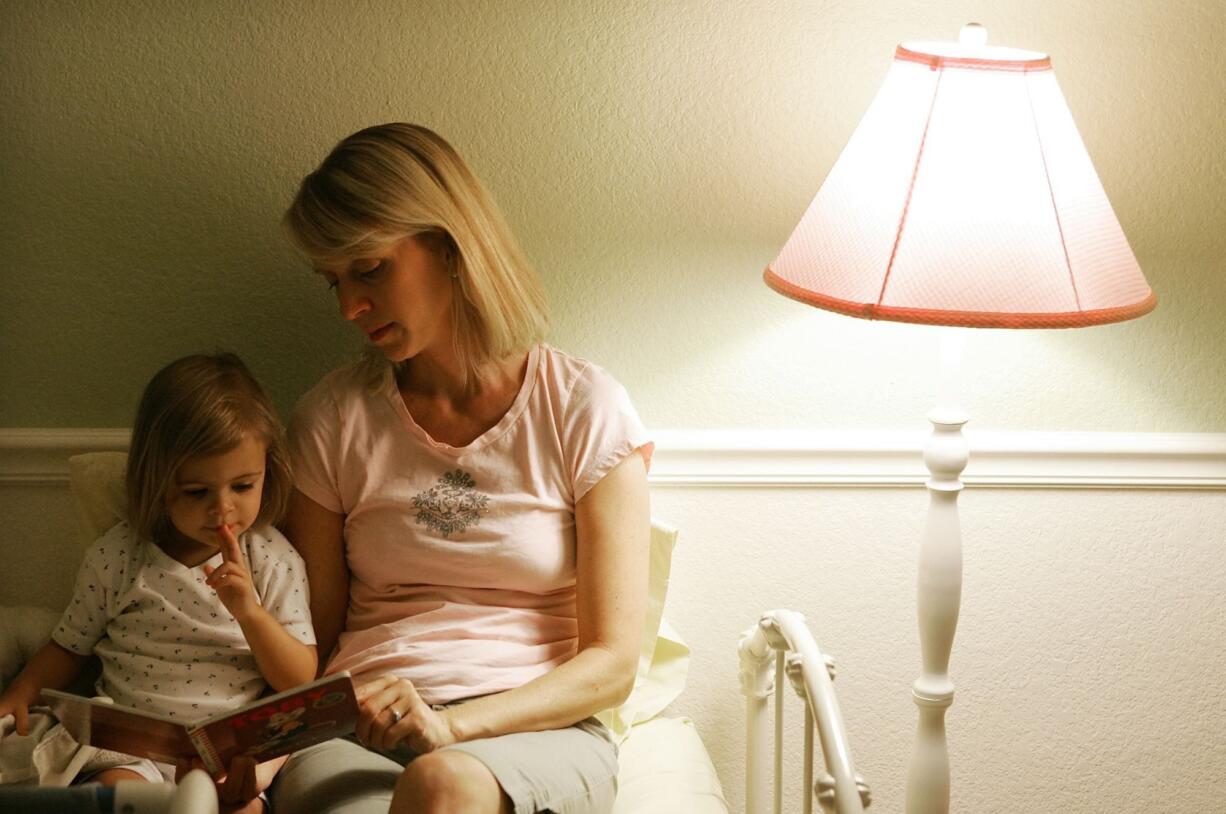 Allysa Adams, right, reads a bedtime story to her younger daughter, Andie Adams Urbinato, 2 1/2, at their home in Phoenix, Ariz. in this 2007 file photo.