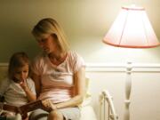 Allysa Adams, right, reads a bedtime story to her younger daughter, Andie Adams Urbinato, 2 1/2, at their home in Phoenix, Ariz. in this 2007 file photo.