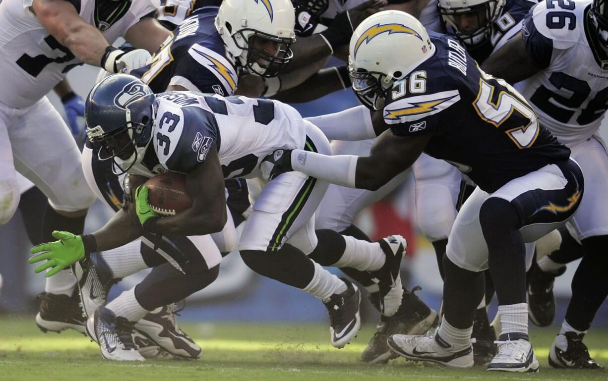 Seattle Seahawks running back Leon Washington (33), left, is held up by San Diego Chargers linebacker Donald Butler during the first half Thursday.