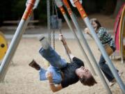 Sean Snyder and his daughter, Chloe Snyder, 9, play on the swings at Orchards Community Park in Orchards.