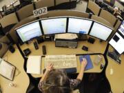 A 911 dispatcher works several computer screens, keeping track of officers with the Clark County Sheriff's Office and six other police departments.