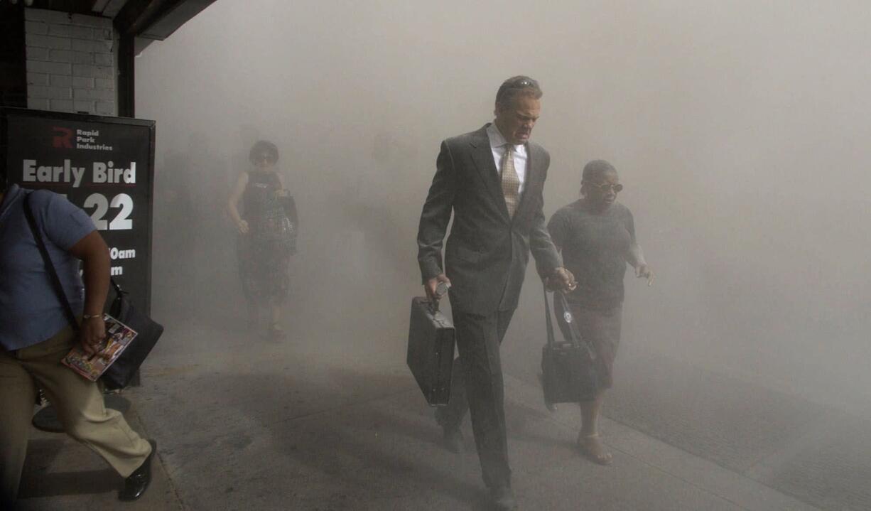 Pedestrians flee the dust-filled area surrounding the World Trade Center following the Sept.