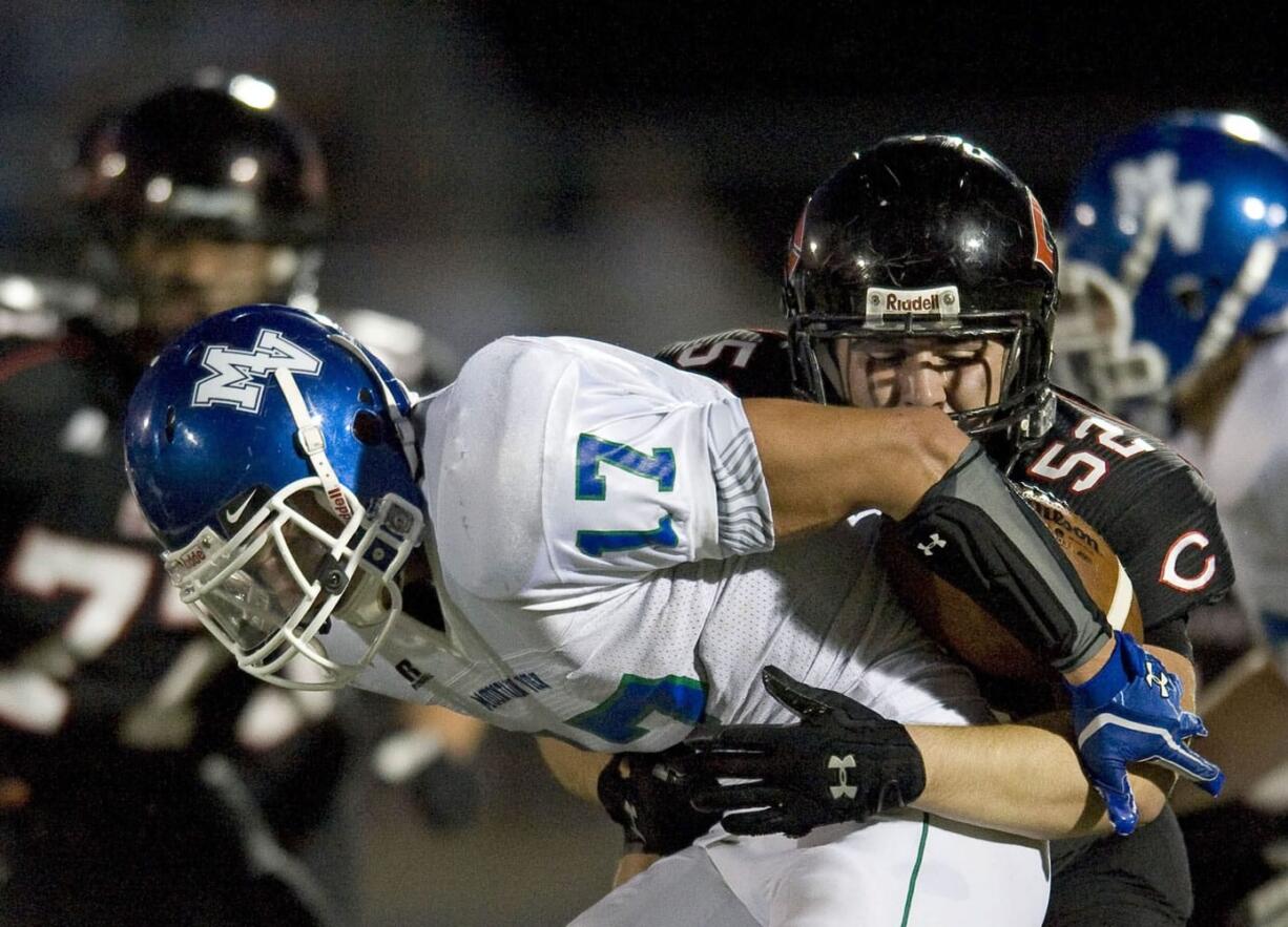 Scott Feather (52) of Camas forces a fumble by Mountain View's Justin Rinta (17) which was recovered and returned 16 yards for a touchdown by Camas' John Norcross during the second quarter at Doc Harris Stadium on Friday.