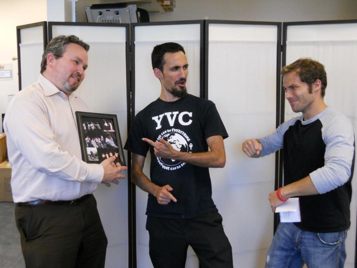 Lance Christian, left, executive director of the Portland ALS Association chapter, jokes around with Rashid Al-Robaee, center, and Paul Richter while being presented with a check for more than $1,100.